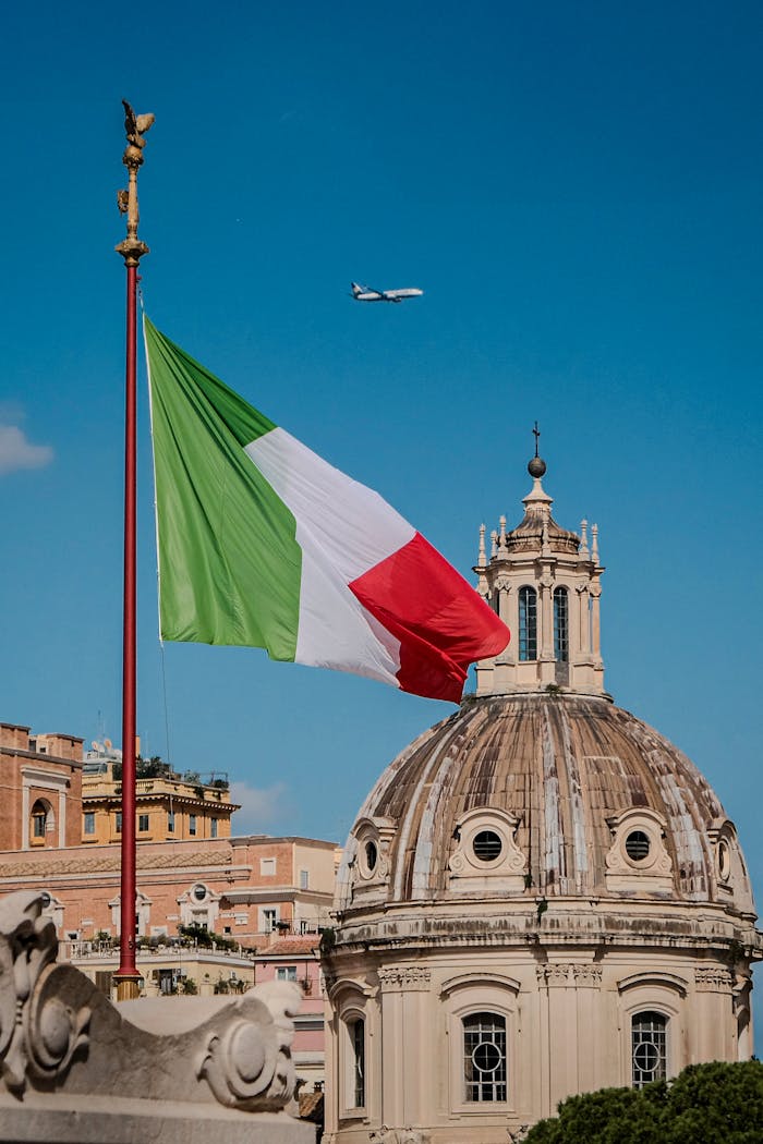 Captivating view of the Italian flag against Roman architecture and blue sky.